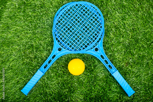 children tennis rackets and a ball on a green lawn, summer outdoor sport activities