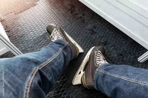 Close-up detail view of male person legs wearing jeans and black rental skating boots standing on non-slip rubber soft mat in dressing room locker skating rink. Healthy recreation leisure activity