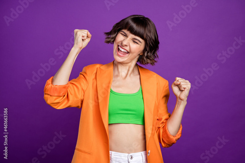 Photo of hooray millennial brunette lady hands fists wear orange cardigan isolated on violet color background