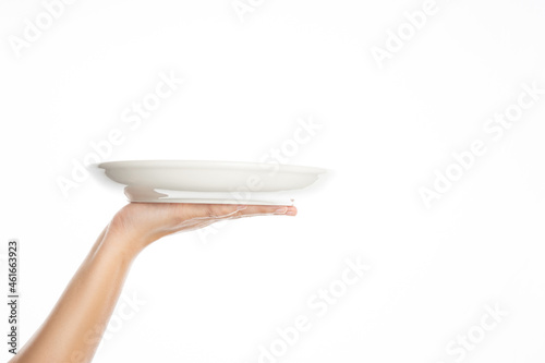 One white kitchen plate on human hand on white background