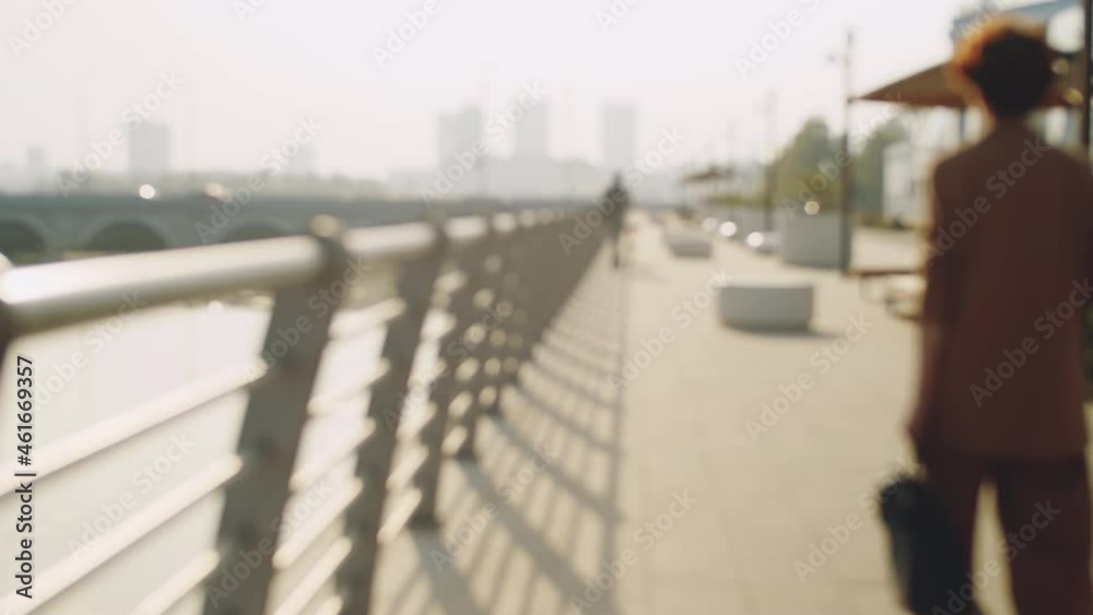Defocused shot of business people walking on embankment in city on summer day Defocused shot of business people walking on embankment in city on summer day