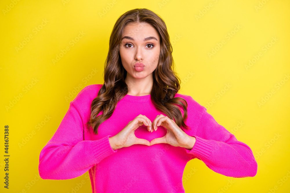 Photo of young attractive girl happy positive smile pouted lips show fingers heart symbol isolated over yellow color background Photo of young attractive girl happy positive smile pouted lips show fingers heart symbol isolated over yellow color background