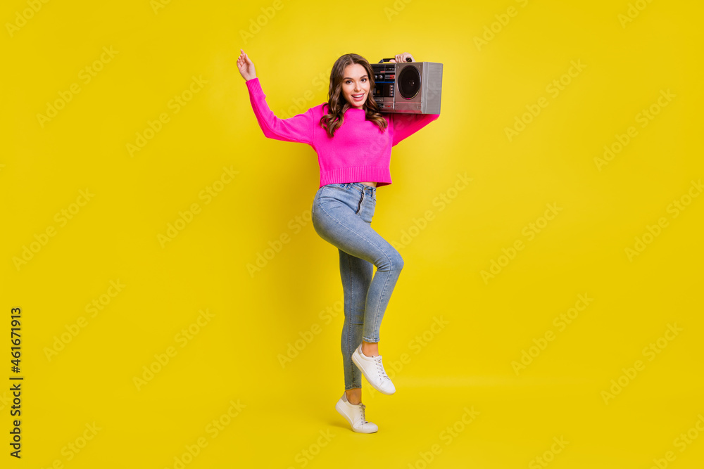 Full size photo of young attractive girl happy positive smile hold retro boombox music isolated over yellow color background Full size photo of young attractive girl happy positive smile hold retro boombox music isolated over yellow color background
