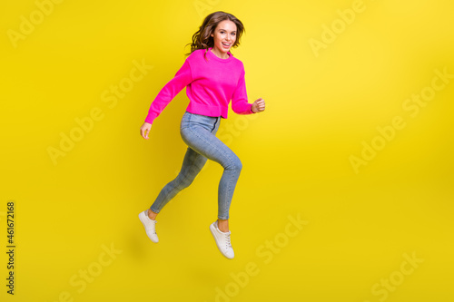 Full length photo of adorable purposeful wavy young woman wear pink sweater jumping running isolated yellow color background