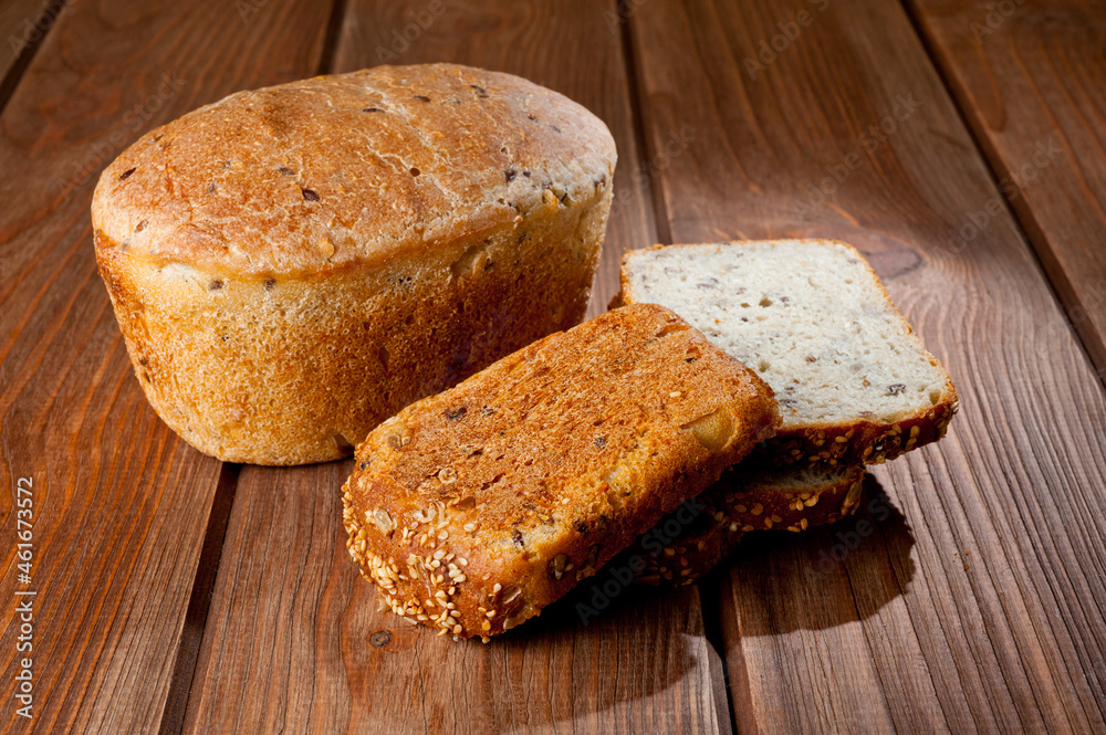 A loaf of delicious white bread made from natural products, on hops with flax saturation, without baker's yeast, on a wooden table surface. A loaf of delicious white bread made from natural products, on hops with flax saturation, without baker's yeast, on a wooden table surface.