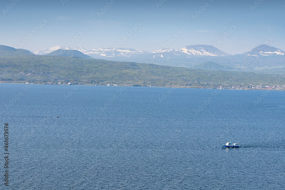Ferry boat or fishing ship transporting passengers on Lake Sevan in Armenia. Water cruise and tours concept