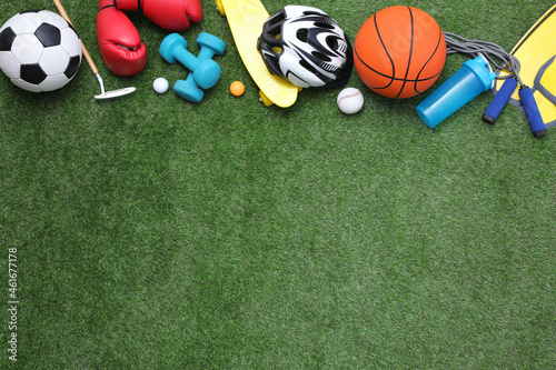 Different sport equipment on green grass  flat lay. Space for text