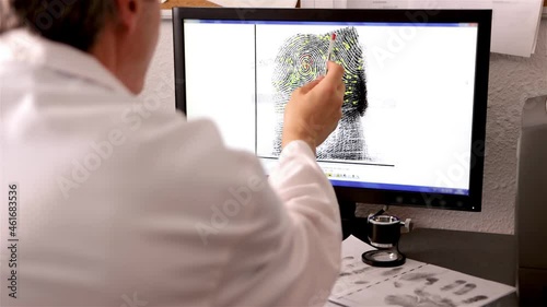 An expert in police science, csi, checks a fingerprint and its matching points on a computer screen photo