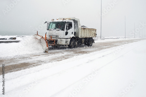 Truck cleaning  winter road covered with snow at the sea side park