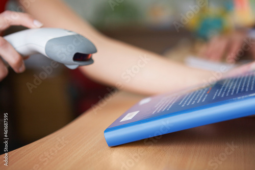 Close-up of student's hands scanning book bar code in library