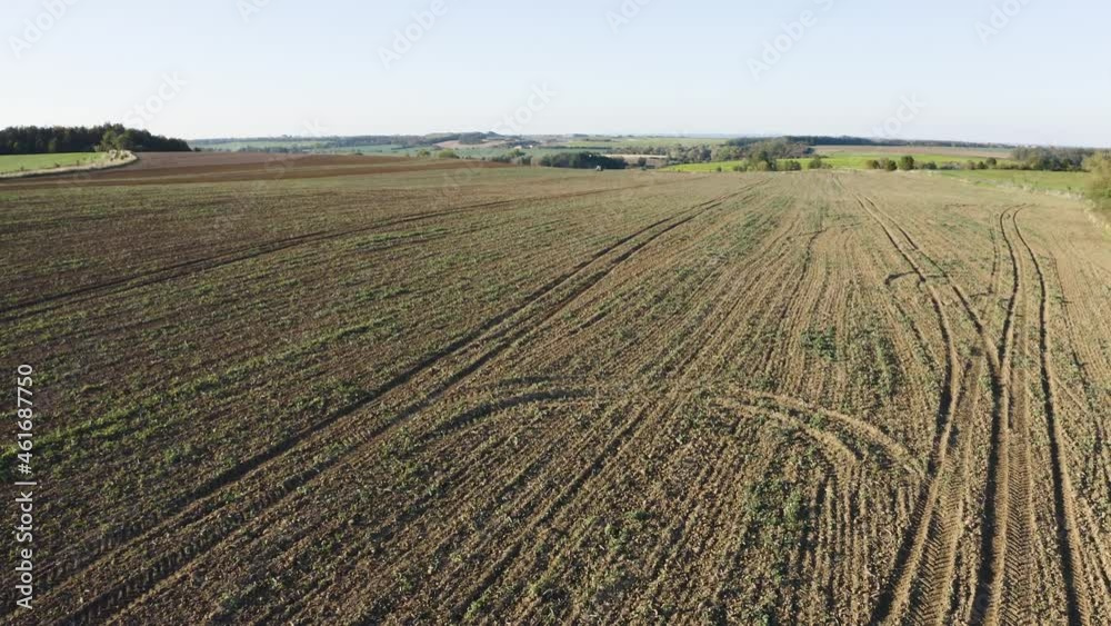 Aerial drone shot - a field with a tractor and a road in a rural area on a sunny day - drone ascends fast off the ground Aerial drone shot - a field with a tractor and a road in a rural area on a sunny day - drone ascends fast off the ground