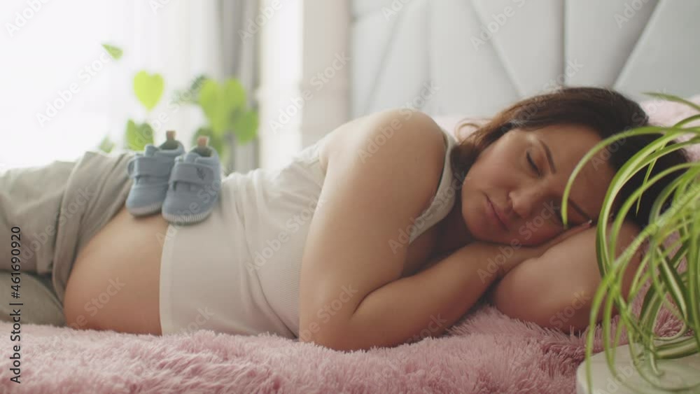 Pregnant woman expecting a baby resting in the bedroom. Pregnant adult woman sleeping at home alone. Woman pregnancy and maternity prenatal care. Slow motion 4K video. Pregnant woman expecting a baby resting in the bedroom. Pregnant adult woman sleeping at home alone. Woman pregnancy and maternity prenatal care. Slow motion 4K video.