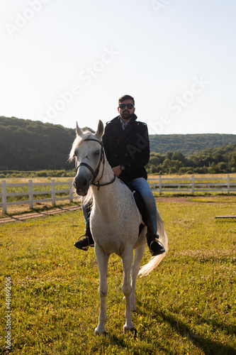 The young man is riding a horse on a farm