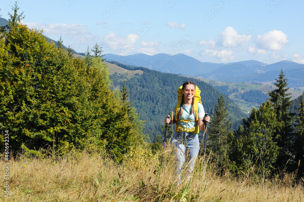 Woman with trekking poles hiking in mountains