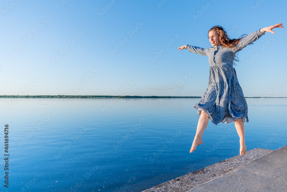 Obraz premium Adult woman in blue dress and straw hat walking near the river. Fortieth people.
