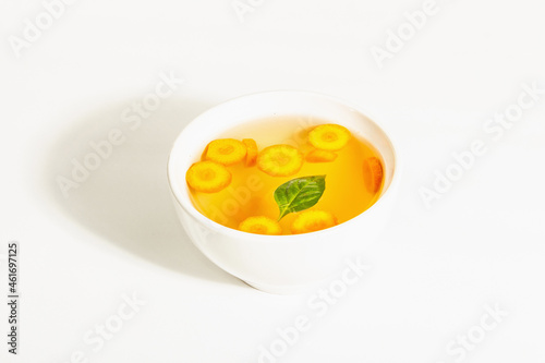 Transparent chicken broth with vegetables in ceramic bowls