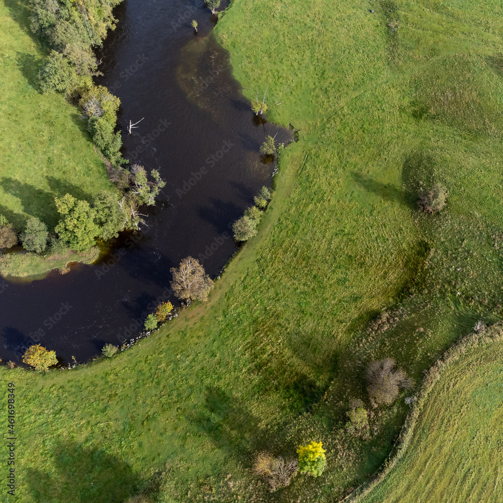 Aerial, drone photography of river, green fields and trees. Photography taken in Sweden in autumn, October. Copy space and place for text.