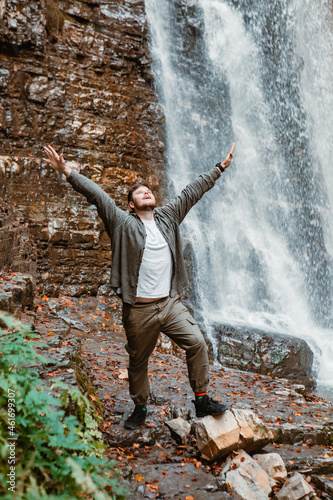 young strong man hiker looking the waterfall