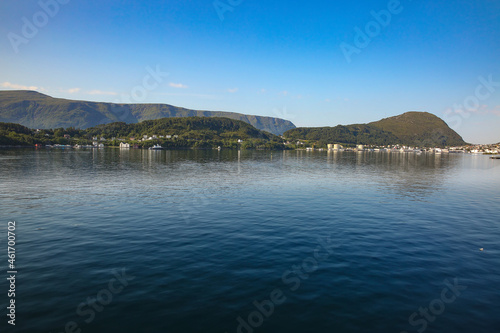 View of the beautiful landscape of the archipelago, islands and fjords with reflections of the land in the ocean, from the port of Alesund, Norway.