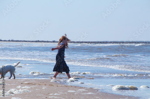 Young girl playing on. the Cromer beach in a sunny day of summer, joy, happiness, holiday, vacation in England, United Kingdom, Norfolk coast, North sea
