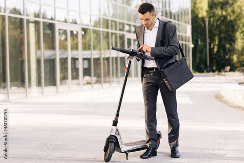 Man uses an electric scooter as a modern means of transportation in the city. A male businessman approaches an electric scooter and using mobile phone app. Ecological transportation photo