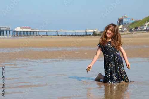 Young girl playing on. the Cromer beach in a sunny day of summer, joy, happiness, holiday, vacation in England, United Kingdom, Norfolk coast, North sea
