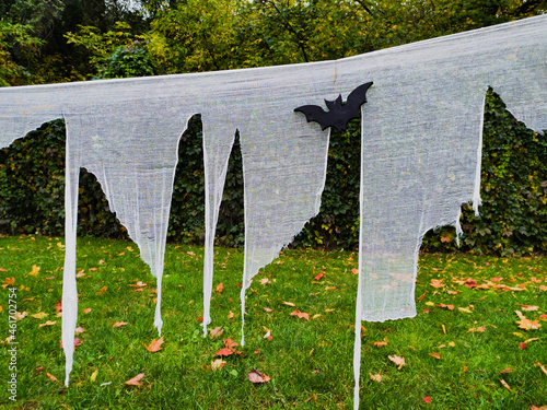 Decorations as symbol of Halloween, white cutted cheesecloth in city park photo