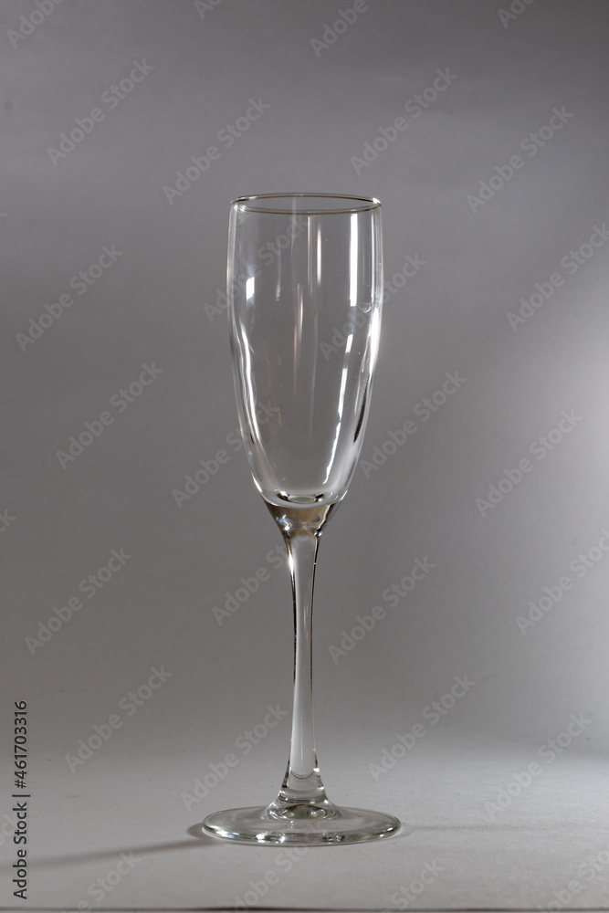 Glass champagne glass, on a light gray background. Glassware on the background of Whatman. Glass champagne glass, on a light gray background. Glassware on the background of Whatman.
