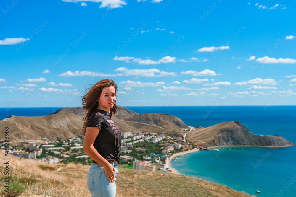 A young beautiful woman on a high mountain overlooking the coast of the village of Ordzhonikidze in the Crimea, the concept of travel