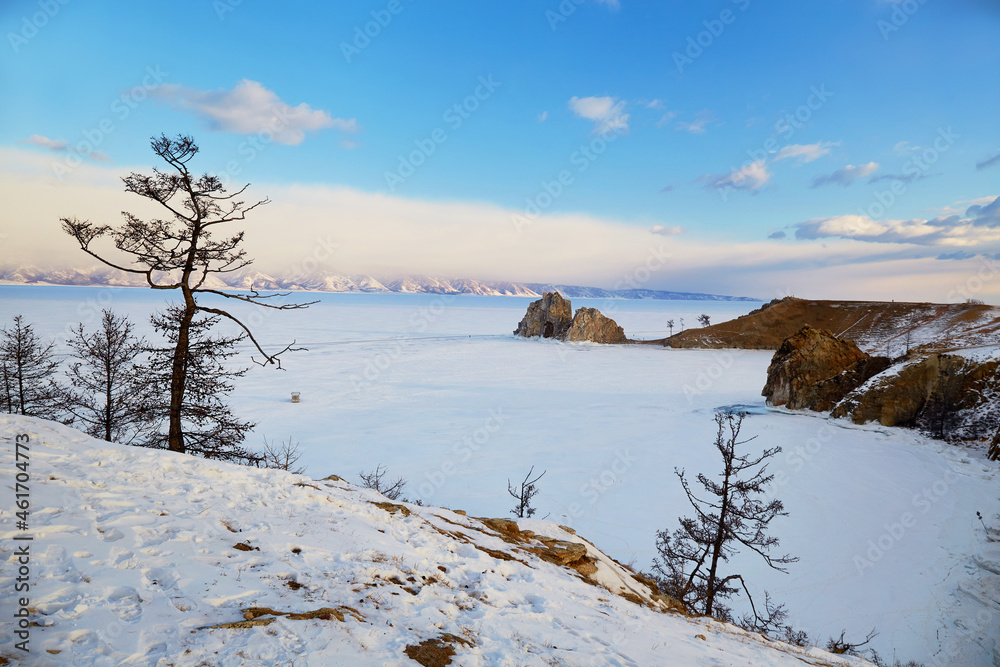 View of Cape Burhan or Shaman rock on Olkhon island in winter. Frozen Lake Baikal, snow on the surface of the ice. View of Cape Burhan or Shaman rock on Olkhon island in winter. Frozen Lake Baikal, snow on the surface of the ice.