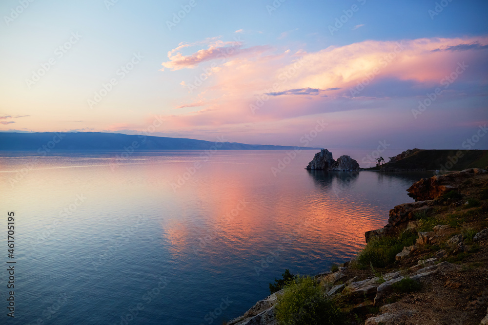 Lake Baikal on a summer evening. Khuzhir Bay, Shamanka Rock or Cape Burkhan at sunset. Beautiful landscape with colorful clouds over the island of Olkhon. 