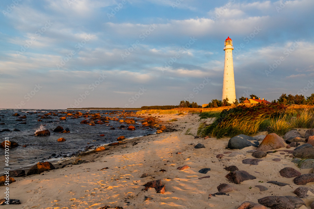 Tahkuna lighthouse on the rocky shore during sunset at Hiiumaa, Estonia, Europe. White lighthouse with red top at sundown. Pink dawn near lighthouse on the windy coast.