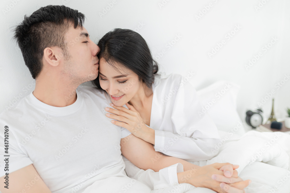 asian lover rest on bed, they use hand hug body together, man kiss on head of woman, they feeling love and happy together, happiness honeymoon and valentine's day asian lover rest on bed, they use hand hug body together, man kiss on head of woman, they feeling love and happy together, happiness honeymoon and valentine's day