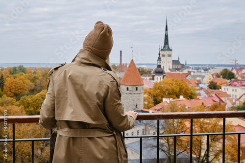 Woman in hat enjoy panorama of the city of Tallinn. Amazing scenic view of the old town. Girl explore Estonia, Europe. City and sea. City autumn landscape, old historical architecture