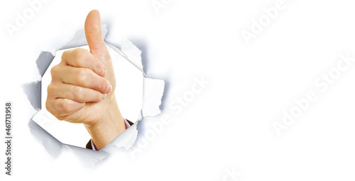 Geschäftsfrau zeigt Daumen hoch durch Riss im Papier photo