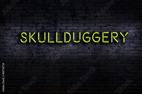 Night view of neon sign on brick wall with inscription skullduggery photo