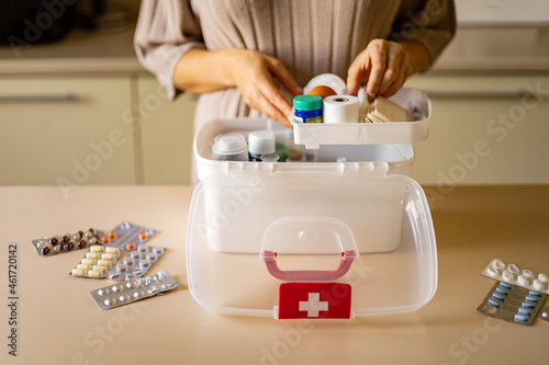 Closeup female hand placing medicament domestic first aid kit. Storage organization emergency supply photo