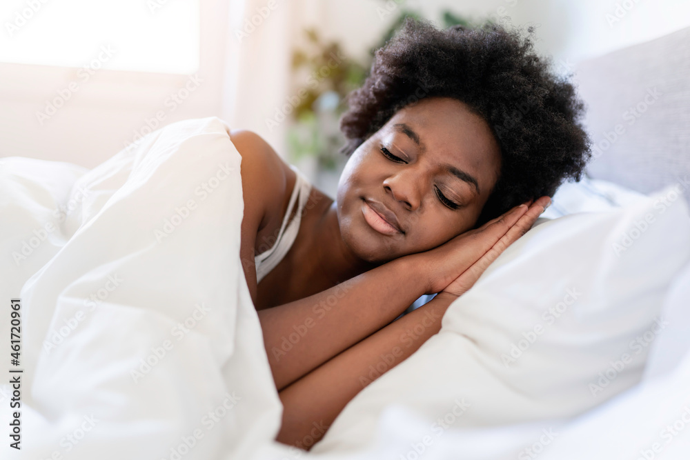 beautiful young African woman in tank top lying in bed sleeping