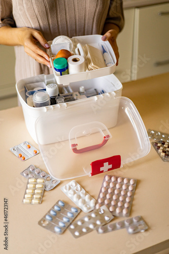 Closeup female hand placing medicament domestic first aid kit. Storage organization emergency supply photo