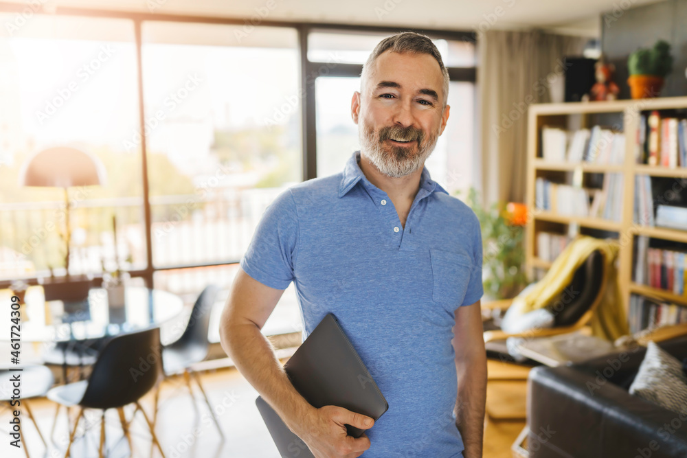 Obraz premium Businessman at home holding his laptop