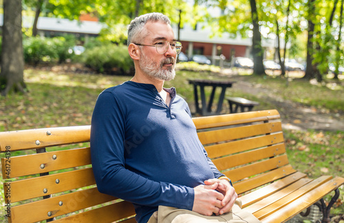 Portrait of a mature man sitting on a bench in an urban park