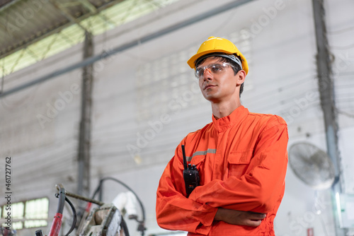 Portrait of male engineer in orange uiform cross arms standing at factory Industrial photo