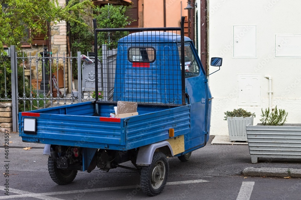 A traditional blue three-wheeled vehicle parked on the road (Tuscany, Italy, Europe)
