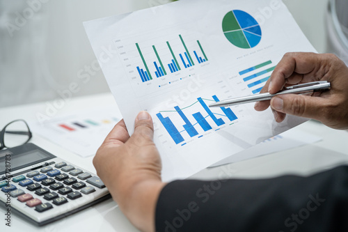 Obraz na płótnie Asian accountant working and analyzing financial reports project accounting with chart graph and calculator in modern office, finance and business concept