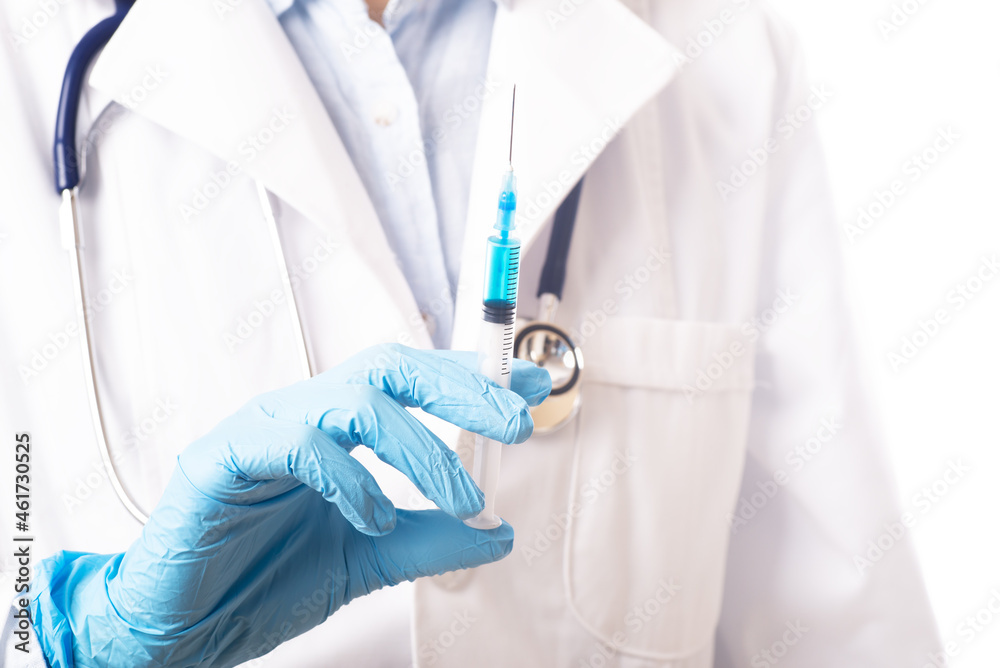 A woman doctor holds a syringe in front of the ward A woman doctor holds a syringe in front of the ward