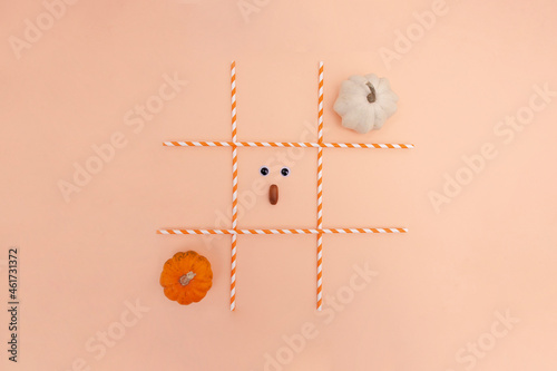 Tic-tac-toe game (OX game) with pumpkins on the orange background. Helloween composition. Creative composition.