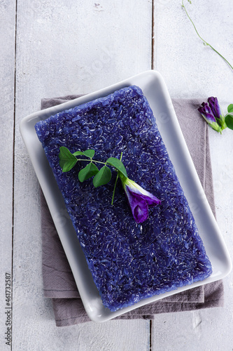 Wajik ketan bunga telang or Wajit Ngora is traditional Indonesian snack made with steamed sticky glutinous rice cooked in Sugar, coconut milk, and bluepea flower juice.  photo