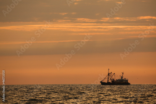 A fishing boat on the open sea at sunset © RMMPPhotography