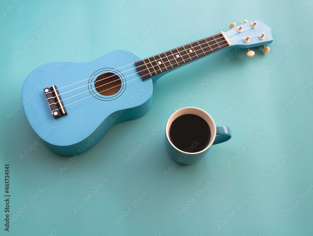 Obraz premium Blue ceramic cup with black coffee put beside Ukulele