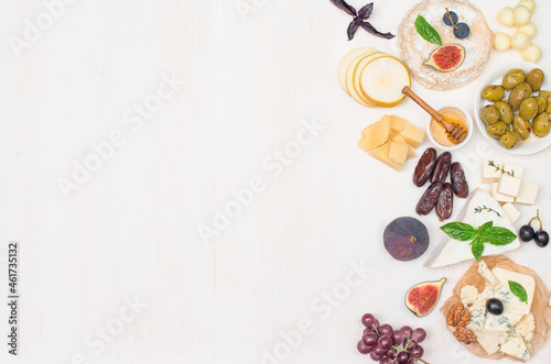 Various type of cheese grapes dates nuts fig and honey on white background with copy-space.